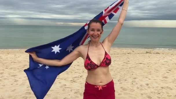 Smiling woman spinning around with Australian flag in her hands. Slow motion. — Stockvideo