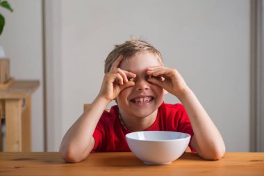 Kahvaltıda tahıl gevreğiyle oynayan tatlı çocuk. Yaşam tarzı portresi. Doğal ışık. Özgün ifadeler.