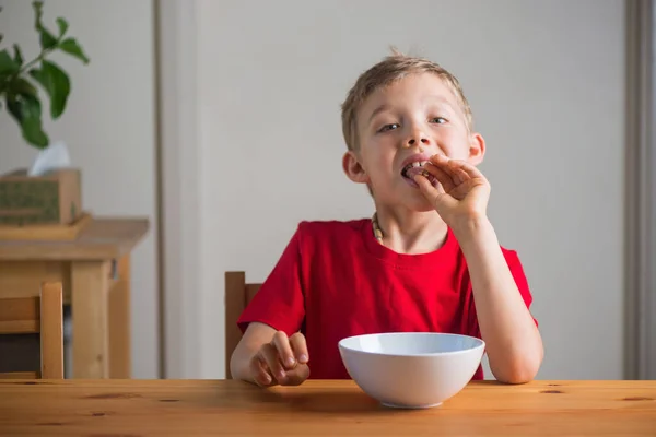 Το χαριτωμένο αγόρι τρώει γκρανόλα για πρωινό. Πορτρέτο τρόπου ζωής. — Φωτογραφία Αρχείου
