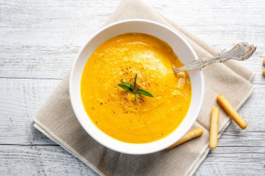 Arka planda keten peçeteli balkabağı çorbası.
