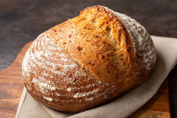 Kahverengi doğrama tahtasındaki keten kumaşa ekşi ekmek..