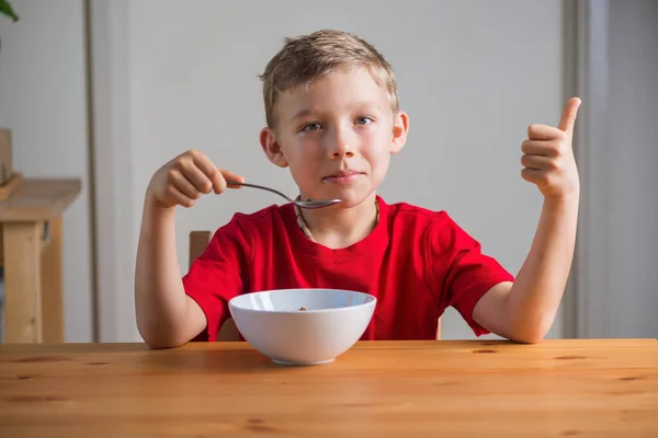 Leuke jongen eet granola als ontbijt. Lifestyle portret. — Stockfoto