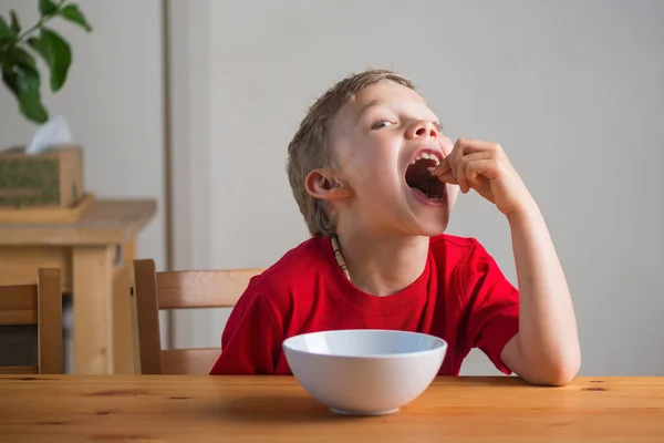Mignon garçon mange granola pour le petit déjeuner. Portrait de style de vie. — Photo