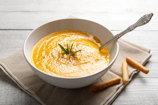 Pumpkin soup on linen napkin on light background. Concept of eating seasonal food, climatarian diet.