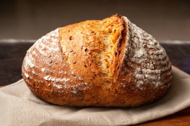 Kahverengi doğrama tahtasındaki keten kumaşa ekşi ekmek. Sıcak ruh hali fotoğrafı. Sağlıklı beslenme kavramı.