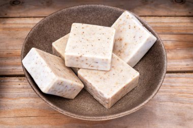 Ahşap arka planda kahverengi kâsede kurutulmuş lavanta çiçekli el yapımı sabun..