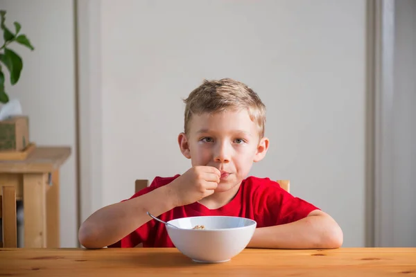 Söt pojke äter granola till frukost. Livsstilsporträtt. — Stockfoto