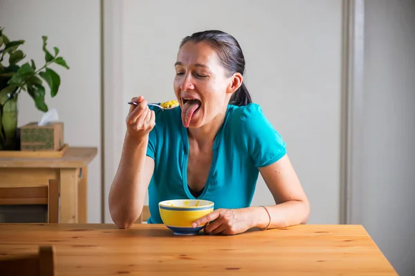 Vrouw die kitchari eet als ontbijt en grappige gezichten trekt. Stockfoto