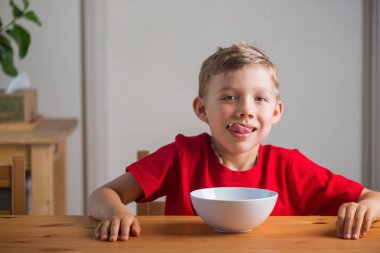 Kahvaltıda tahıl gevreğiyle oynayan tatlı çocuk. Yaşam tarzı portresi. Doğal ışık. Özgün ifadeler.