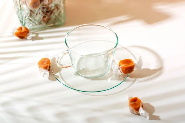 Tazza Vetro Trasparente Alcune Caramelle Caramello Sfondo Chiaro Del Mattino — Foto Stock