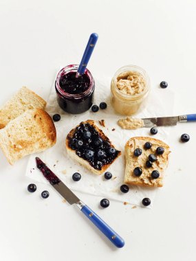 Yaban mersini reçeli ve fıstık ezmeli beyaz ekmek tostu. Sığ dof.