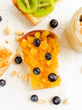 Meyveli, böğürtlenli, reçelli ve fıstık ezmeli beyaz ekmek. Sığ dof.