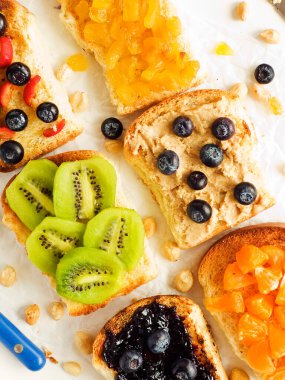 Meyveli, böğürtlenli, reçelli ve fıstık ezmeli beyaz ekmek. Sığ dof.