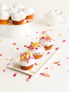 Krem şantili ve yenilebilir çiçekli kekler. Sığ dof.