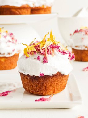 Krem şantili ve yenilebilir çiçekli kekler. Sığ dof.