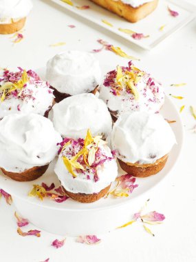 Krem şantili ve yenilebilir çiçekli kekler. Sığ dof.