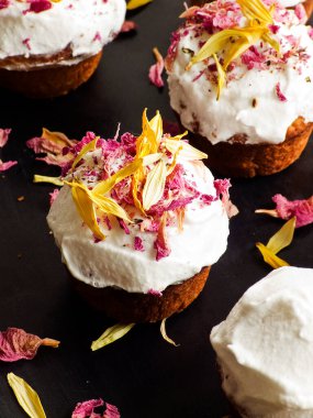 Krem şantili ve yenilebilir çiçekli kekler. Sığ dof.