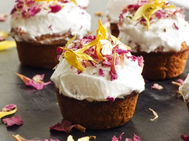 Krem şantili ve yenilebilir çiçekli kekler. Sığ dof.