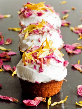 Krem şantili ve yenilebilir çiçekli kekler. Sığ dof.