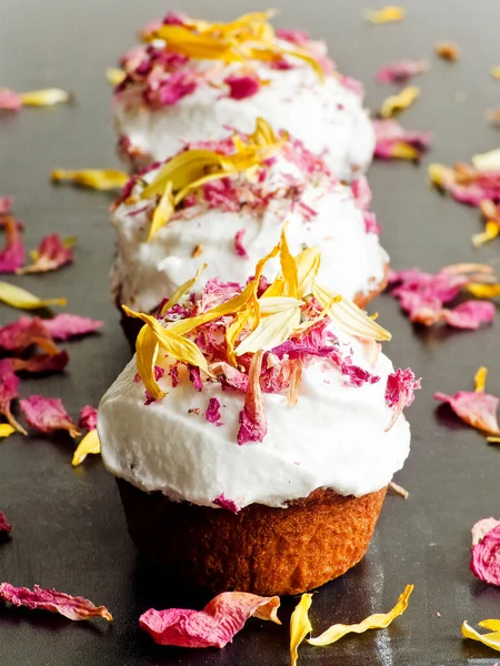 Krem şantili ve yenilebilir çiçekli kekler. Sığ dof.