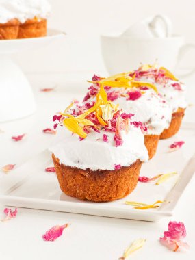 Krem şantili ve yenilebilir çiçekli kekler. Sığ dof.