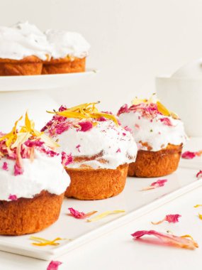 Krem şantili ve yenilebilir çiçekli kekler. Sığ dof.