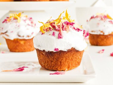 Krem şantili ve yenilebilir çiçekli kekler. Sığ dof.