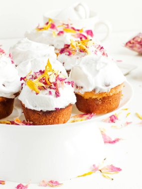 Krem şantili ve yenilebilir çiçekli kekler. Sığ dof.