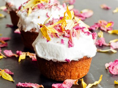 Krem şantili ve yenilebilir çiçekli kekler. Sığ dof.