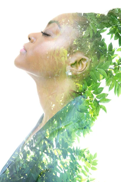 A profile portrait of a woman dissolving into green twigs. Double exposure technique. — Stock Photo, Image