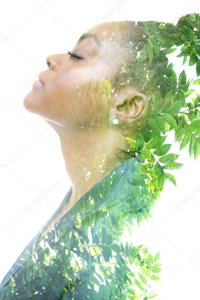 A profile portrait of a woman dissolving into green twigs. Double exposure technique.