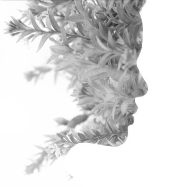 Çift pozlama tekniğinde dallarla birleştirilmiş siyah beyaz bir kadın portresi.