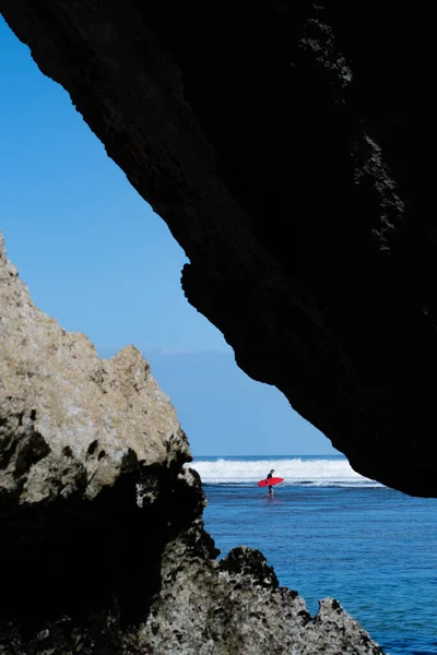 Un bărbat înotând în mare pe placa de surf roşie. — Fotografie, imagine de stoc