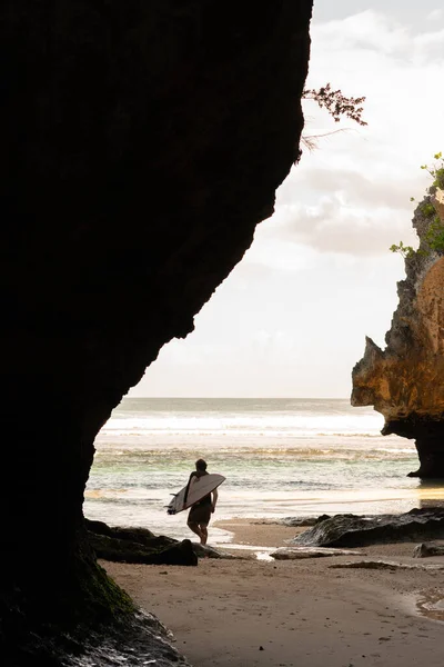 Ein Mann am Strand mit einem Surfbrett. — Stockfoto