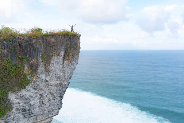 Een man staat op een klif kijkend naar de oceaan — Stockfoto