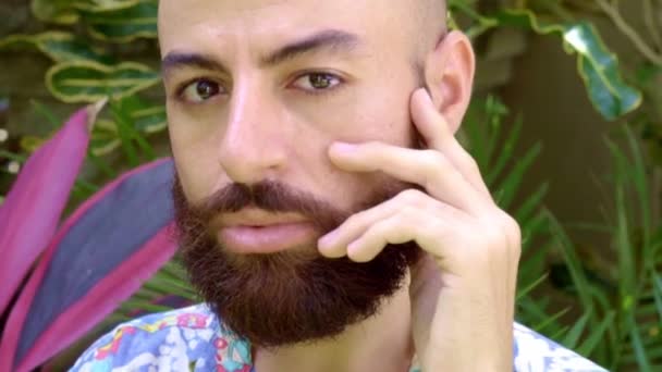 Ένα πορτραίτο ενός γενειοφόρου γκέι άντρα που αλληθωρίζει με το χέρι στο πρόσωπό του — Αρχείο Βίντεο