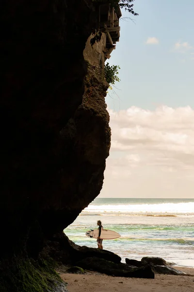 Een man die over het strand loopt met een surfplank. — Stockfoto