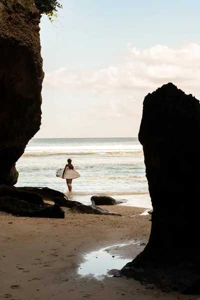 Um homem caminhando na praia com uma prancha de surf. — Fotografia de Stock