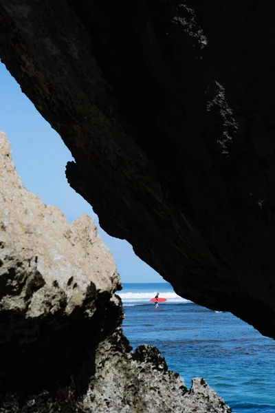 Een man die in de zee zwemt op de rode surfplank. — Stockfoto