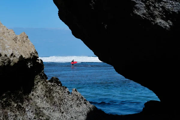 Een man die in de zee zwemt op de rode surfplank. — Stockfoto