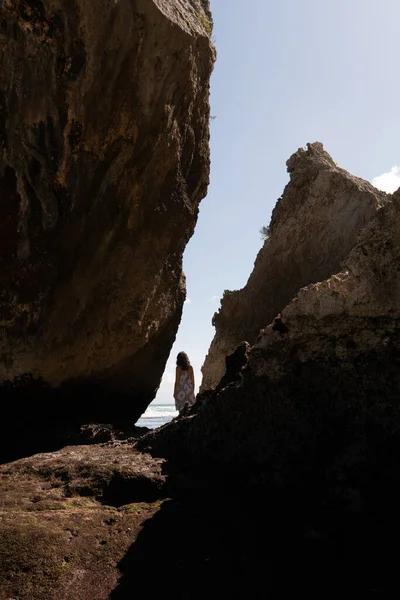 Eine Frau, die auf einem Felsen steht und den Ozean beobachtet. — Stockfoto