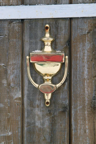 Golden doorknocker on a wood door — Stock Photo, Image