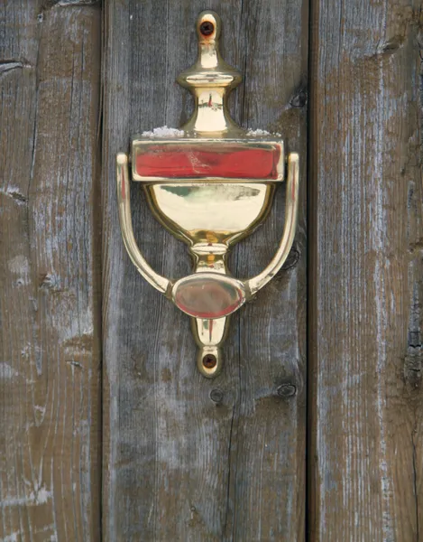 Gyllene doorknocker på en trä dörr — Stockfoto