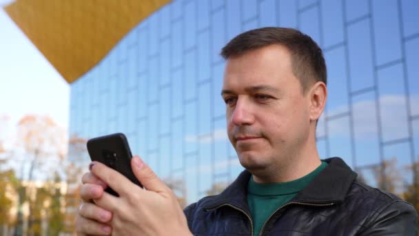 ミレニアル・マンは街で携帯電話を使い晴れた日にタップ — ストック動画