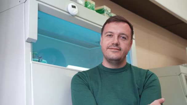 Happy scientist poses in room with laboratory box in UV light for sterilization in background — Stockvideo