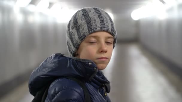 冬には都市の地下の屋根付き歩道で帽子とジャケットで一人で自信の少年の肖像画 — ストック動画