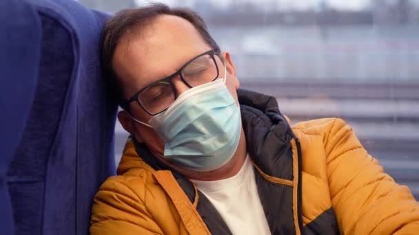 Moe millennial man met medisch masker en misvormde glazen zitten in de buurt venster in metro trein in de stad — Stockvideo