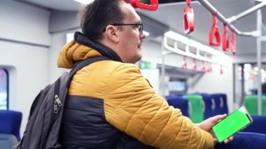 Adamın arka planı yeşil ekranlı akıllı telefonu izlemek ve trende internette gezinmek.