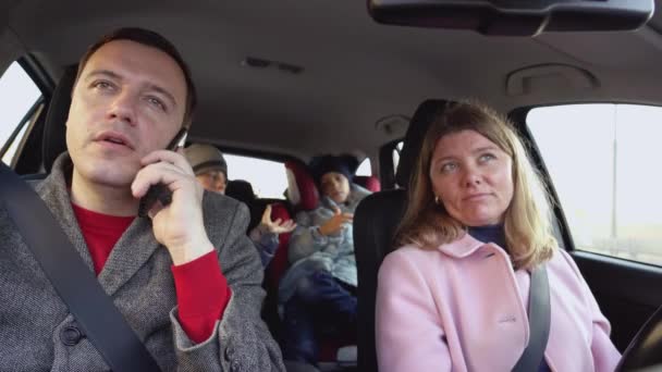 Femme conduit une voiture avec un homme assis sur le siège passager et parlant joyeusement au téléphone du travail — Video