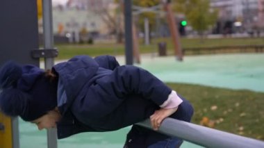 Mutlu kız direğin üzerinde dönüyor. Sonbaharda çocuk parkında eğleniyor.